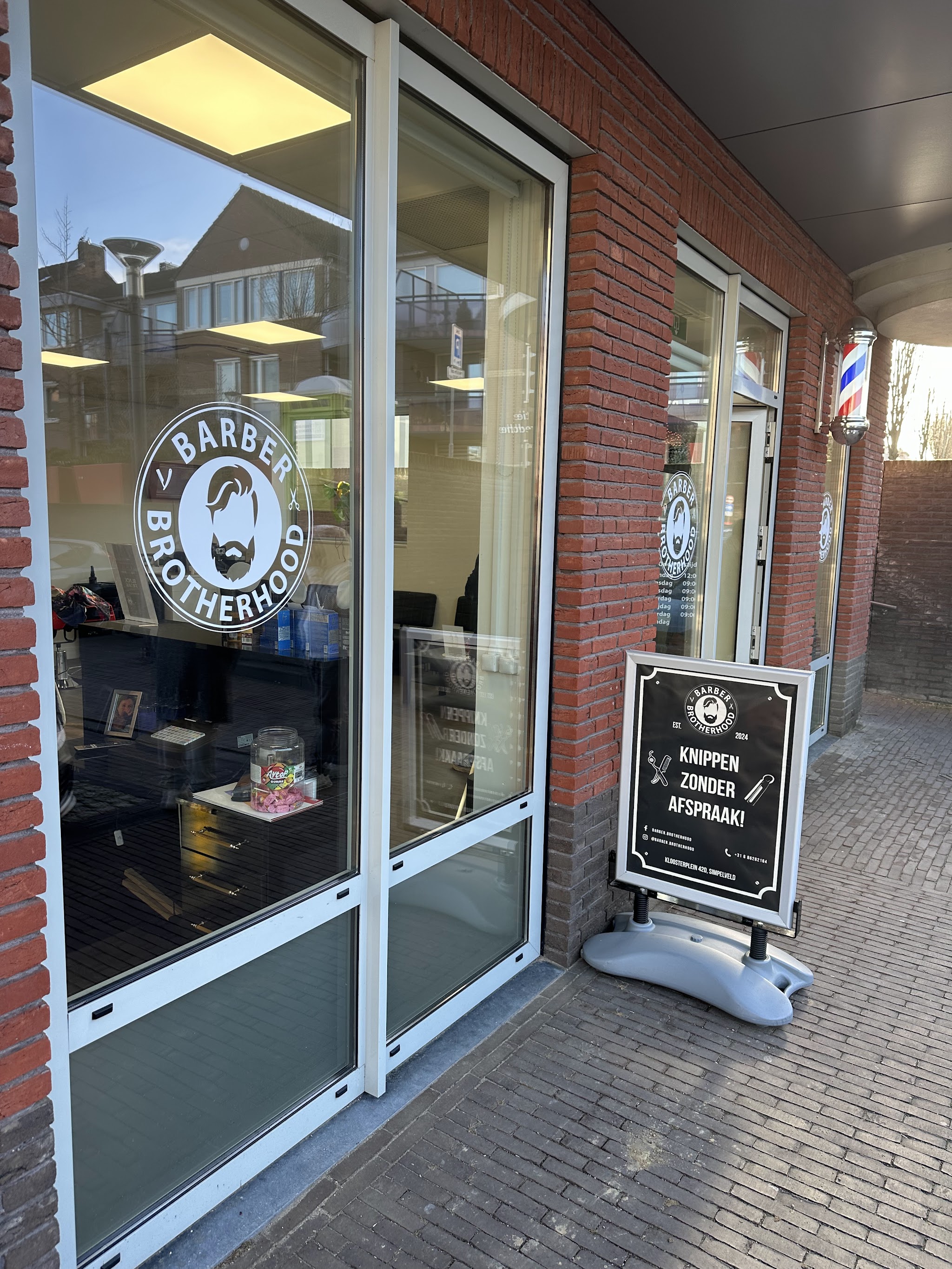 Het raam van de zaak met het logo en het bord 'Knippen zonder afspraak'